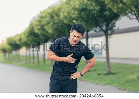 Male asian athlete, has chest pain fitness in the park and running, heart aches after cardio exercise Royalty-Free Stock Photo #2042466854
