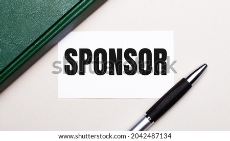 On a light gray background lies a pen, a green notebook and a white card with the text SPONSOR. Business concept.