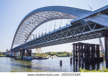 Construction of a large arched bridge in the capital of Ukraine. Podolsky bridge, panoramic view of the bridge under construction across the Dnipro, clear weather, summer. Kyiv Royalty-Free Stock Photo #2042501684