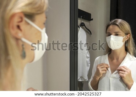 Reflection Of Mature Woman Trying Clothes In Store