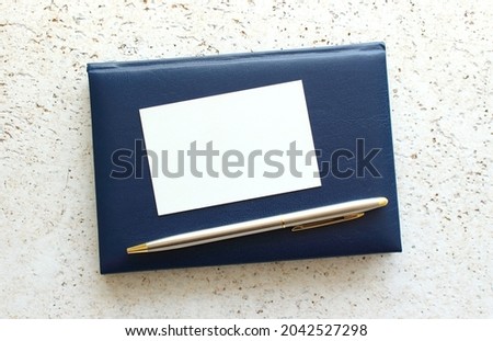 Business card lying on a blue notebook next to the pen. Business concept.