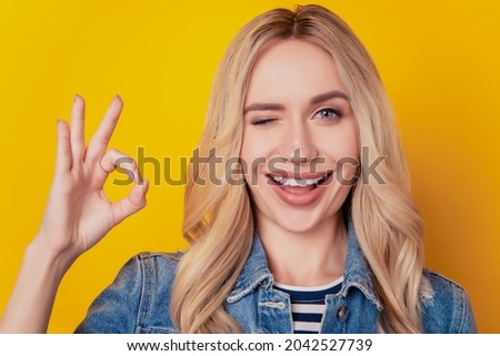 Portrait of suggesting dreamy lady show okey gesture blink eye on yellow background