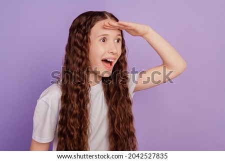 Photo of excited happy little girl look forward empty space isolated on purple background