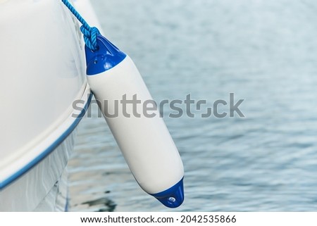 White fenders suspended between a boat and dockside for protection. Maritime fenders Royalty-Free Stock Photo #2042535866