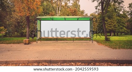 Empty bus stop with mockup space on sidewalk of suburban street at autumn season front view.