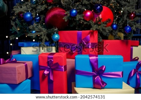 Colorful boxes with gifts near the Christmas tree.