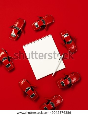 Red cars on a red background with space for notes and a pen. Creative, trendy approach to copy space 