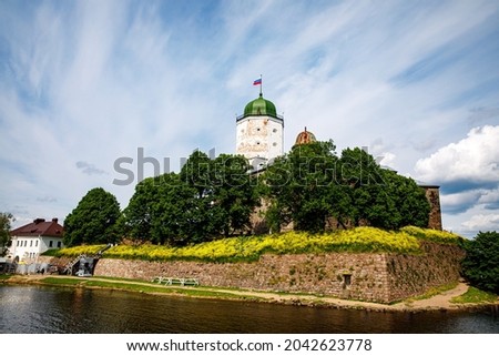 Vyborg Castle (Swedish-built) with Olaf's (st. Olav) Tower with russian flag on the roof. Estuary Vuoksa. Russia on island against the blue sky with clouds
