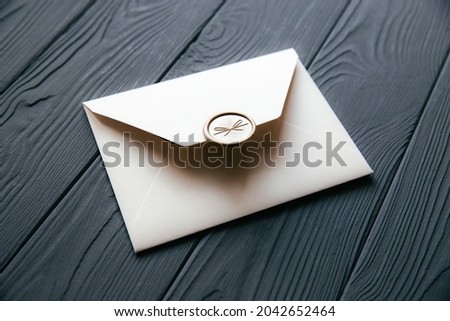 Beige envelope on a dark gray wooden table background. Invitation envelope for wedding, holiday, birthday, party invitation, Christmas envelope. Cose up photo. Royalty-Free Stock Photo #2042652464