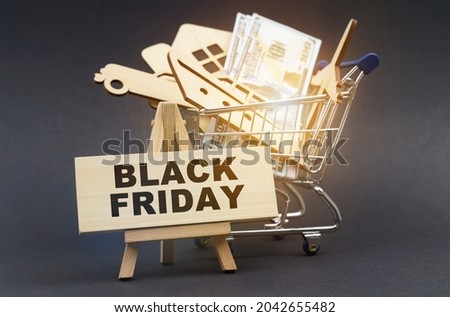 Business and finance concept. On a black background, there is a shopping cart with purchases, next to an easel and a sign with the inscription - BLACK FRIDAY