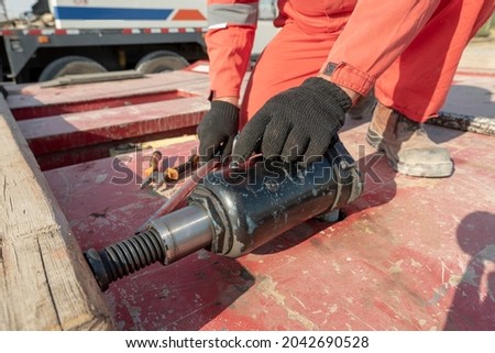 A worker presses down a wooden block with a hydraulic jack Royalty-Free Stock Photo #2042690528