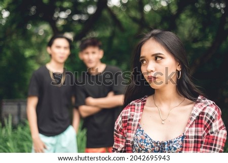 A young woman walking by herself is worried about two rude men catcalling and from behind. Possible stalkers following her. Street harassment. Royalty-Free Stock Photo #2042695943