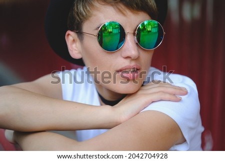 Close up portrait of female hipster with natural makeup and short haircut enjoying leisure time outdoors
