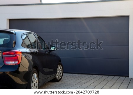 Modern black garage door with car parked in front Royalty-Free Stock Photo #2042709728