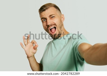 Handsome man isolated over white wall background posing showing okay gesture. Take a selfie.