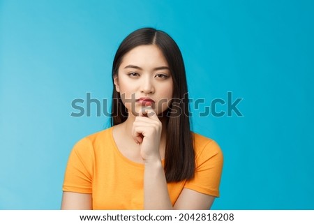 Close-up serious-looking suspicious female asian look disbelief, pondering, solving riddle, squinting hesitant disbelief, frowning suspect something wrong, thinking, focus stare, blue background Royalty-Free Stock Photo #2042818208