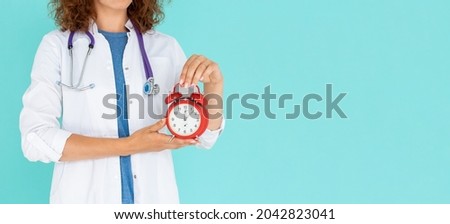 Woman doctor holding an alarm clock isolated on blue background