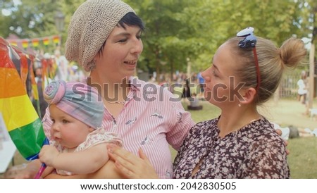 Happy LGBT family with baby on Pride festival to commemorate the culture of the movement for their equality and enlightenment, education against homophobia and transphobia. Child with a rainbow sign. Royalty-Free Stock Photo #2042830505