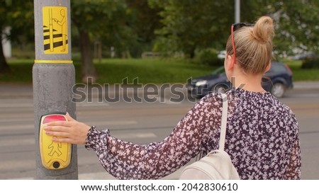 Female pedestrian presses a traffic light button to cross the road. The innovative contactless push button for pedestrians integrates perfectly into the hygiene standards that are currently required.