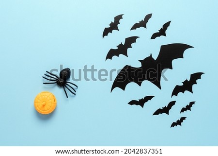 Halloween composition. Spider, pumpkin and bats on a pastel blue background. Top view, flat lay