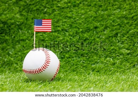 Baseball with flag of America is on green grass