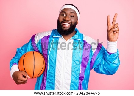 Photo of young african man happy positive smile show peace cool v-sign sportsman player isolated over pink color background