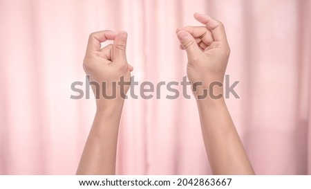 Hands snapping fingers isolated on pink background. Isolated female hands flicking fingers to the rhythm of the music. Sign language.