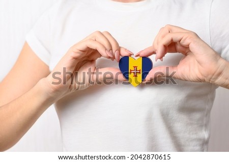Flag of Madeira in the shape of a heart in the hands of a girl. Love Madeira.