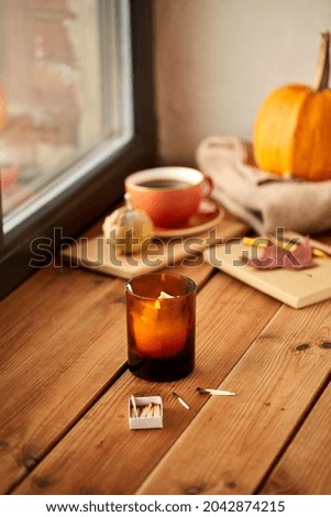 season and objects concept - candle and matches in matchbox on window sill in autumn