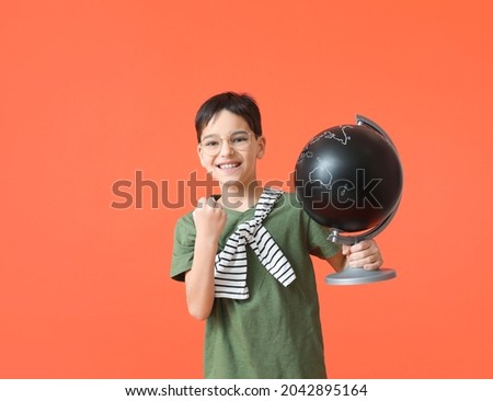 Happy little boy with globe on color background