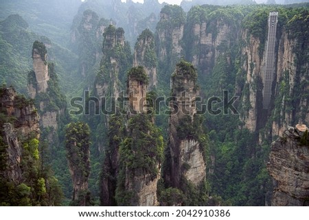 Horizontal view on a breathing Bailong elevator and the karst rock formations in Laowuchang spot of Wulingyuan Scenic Area, Zhangjiajie, Hunan, China. Background, sunset picture 
