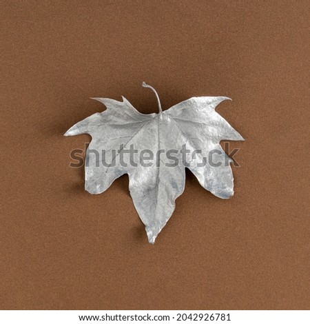 Creative autumn silver dry leaves on a brown background. Holiday concept. Flat lay.