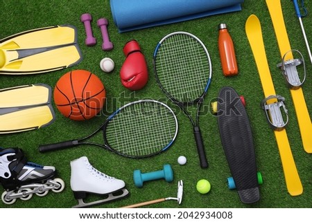 Different sport equipment on green grass, flat lay Royalty-Free Stock Photo #2042934008