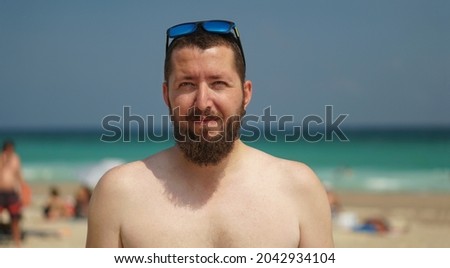 An authentic portrait of a young confident bearded man looking at the camera. Closeup side view of a young natural man on the beach. Concept of success, happiness, positivity, confidence.