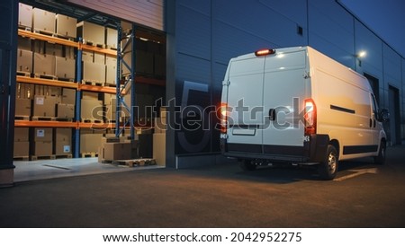 Outside of Logistics Distributions Warehouse and Delivery Van Ready to Ride. Truck Delivering Online Orders, Purchases, E-Commerce Goods, Wholesale Merchandise. Evening Shot with Stop Lights on. Royalty-Free Stock Photo #2042952275