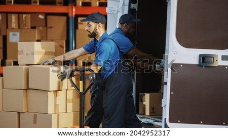 Outside of Logistics Distributions Warehouse: Diverse Team of Two Workers Talk, Joke Around Loading Delivery Truck with Cardboard Boxes, Online Orders, Medicine, Food Supply, E-Commerce Goods Royalty-Free Stock Photo #2042952317