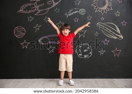 Cute little boy near black wall with drawn space Royalty-Free Stock Photo #2042958386