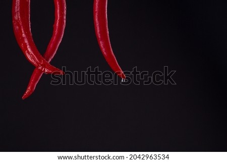 Red crossed chili tails with drops. Royalty-Free Stock Photo #2042963534