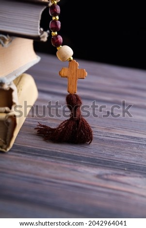 Rosary with cross on stack of holy books.