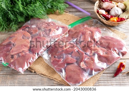 Frozen offal, liver, heart, stomachs in a plastic bag on a wooden table. Frozen products. Frozen food