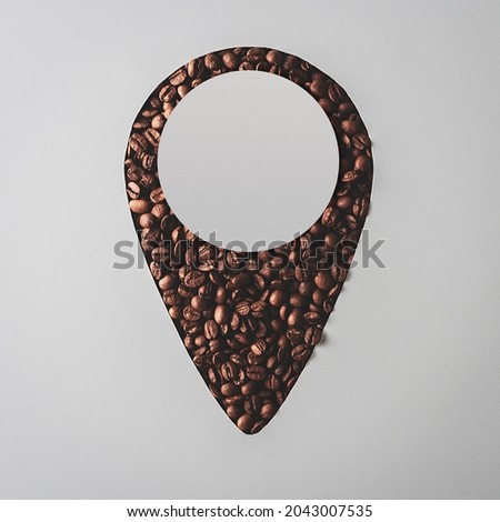 Creative coffee flat lay. Geo-tag with coffee beans with copy space on gray background. 