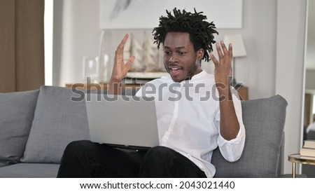 African Man Celebrating Success on Laptop at Home