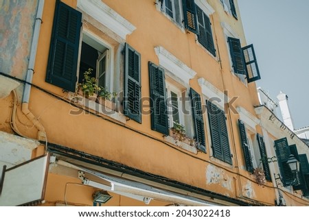 Medieval buildings in Greece island. Photo of local apartment building on streets in Corfu, Kerkira. Windows with shutters. Facades of old houses. Traveling concept.