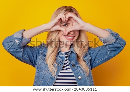 Portrait of affectionate inspired girlfriend show heart gesture cover eye on yellow background