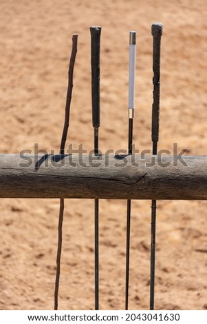 Whips resting on a wooden fence in the riding hall of a riding school