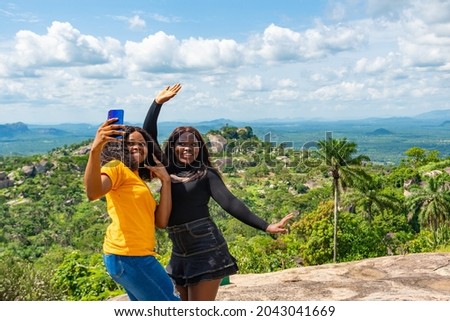young female african friends standing together outdoor on a hike through nature taking selfies