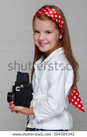 Image of lovely emotional young girl with beautiful hair holds a vintage camera