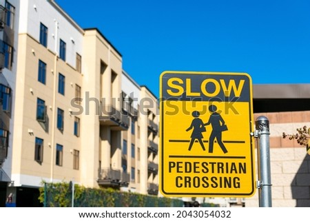 Slow Pedestrian Crossing road sign. Modern mid-rise apartment complex in an urban residential neighborhood