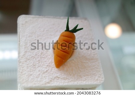 A piece of white cake with small carrot-shaped decorations.