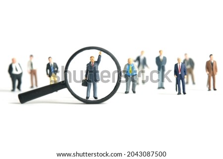 Miniature people toy figure photography. A businessman standing while raise his hand in the people crowd with magnifier glass. Isolated on white background. Image photo